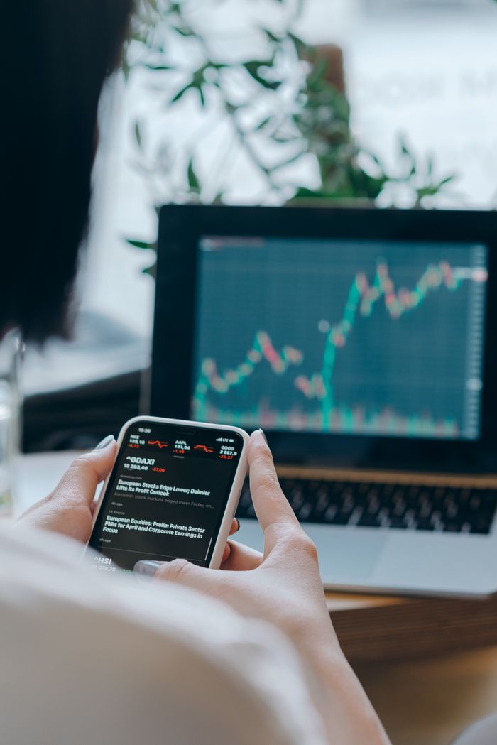 services-03 Person using smartphone for stock market analysis at home office.